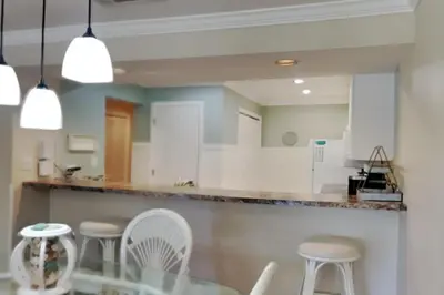 a kitchen with white cabinets and white stools at Edgewater Villa #2409 in Panama City Beach