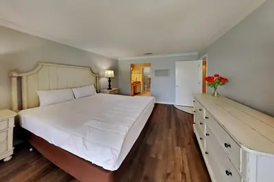 a large bedroom with a large white bed and wooden floors at Edgewater Villa #2409 in Panama City Beach