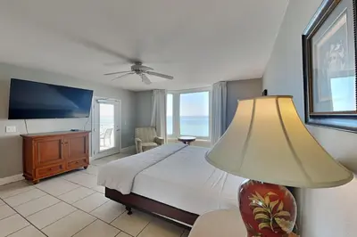 a bedroom with a bed and a tv and a lamp at Emerald Beach #1030 in Panama City Beach