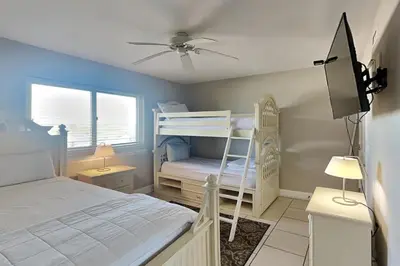 a bedroom with two bunk beds and a tv at Emerald Beach #1030 in Panama City Beach