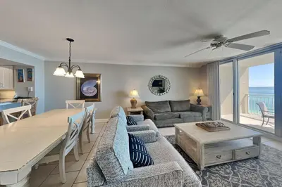 a living room with a table and a couch and a dining room at Emerald Beach #1030 in Panama City Beach