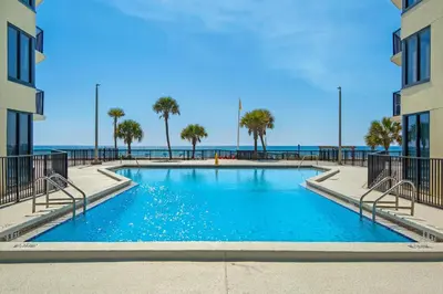 a swimming pool with the ocean in the background at Sunbird 1010E in Panama City Beach