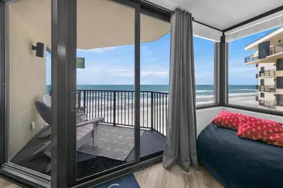 a bedroom with a bed and a balcony with the ocean at Sunbird 1010E in Panama City Beach