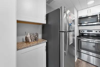 a kitchen with white cabinets and a stainless steel refrigerator at Sunbird 1010E in Panama City Beach