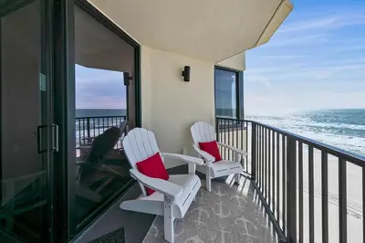 two white chairs sitting on a balcony overlooking the ocean at Sunbird 1010E in Panama City Beach