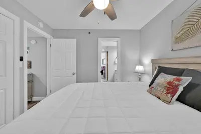 a bedroom with a large white bed with a ceiling fan at Sunbird 1010E in Panama City Beach