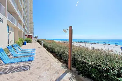 a couple of blue chairs on a sidewalk next to the beach at Majestic Beach Towers 1-1210 in Panama City Beach