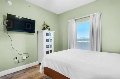 a bedroom with a bed and a tv on the wall at Majestic Beach Towers 1-1210 in Panama City Beach