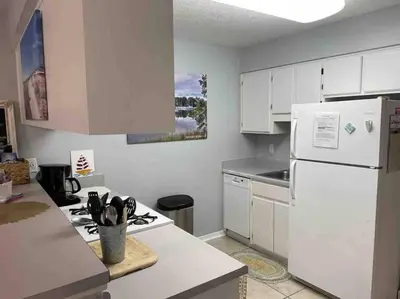 a kitchen with white cabinets and a white refrigerator at Happy Heron, Steps to Beach in Panama City Beach
