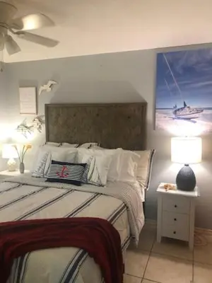 a bedroom with a bed and a lamp and a painting at Happy Heron, Steps to Beach in Panama City Beach