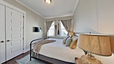 a white bedroom with a bed and a lamp at The Den on 30A in Inlet Beach