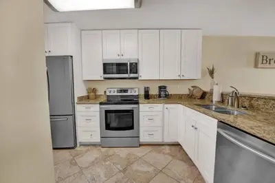 a kitchen with white cabinets and stainless steel appliances at Gulf-Front Seacrest Beach Condo w/ Private Access in Panama City Beach