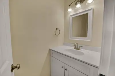 a white bathroom with a sink and a mirror at Gulf-Front Seacrest Beach Condo w/ Private Access in Panama City Beach