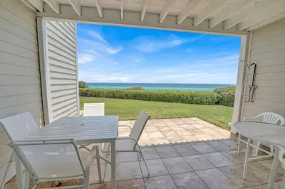 a patio with a table and chairs and a view of the ocean at Gulf-Front Seacrest Beach Condo w/ Private Access in Panama City Beach