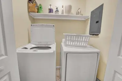 a small kitchen with a stove and a washer and dryer at Gulf-Front Seacrest Beach Condo w/ Private Access in Panama City Beach