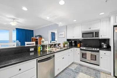 a kitchen with white cabinets and stainless steel appliances at Quiet East End Gulf-Front Condo w/ Heated Pool & Balcony in Panama City Beach