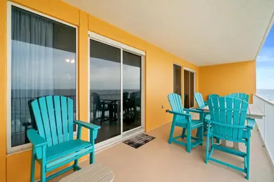 a balcony with three blue chairs and a table at Quiet East End Gulf-Front Condo w/ Heated Pool & Balcony in Panama City Beach