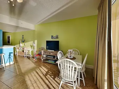a living room with a table and chairs and a tv at Majestic Beach Towers I #405 in Panama City Beach