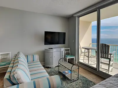 a living room with a couch and a tv and a balcony at Majestic Beach Towers I #1109 in Panama City Beach