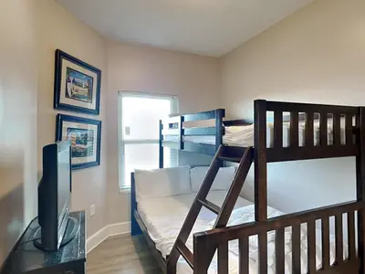 a room with two bunk beds and a television at Majestic Beach Towers II #1204 in Panama City Beach