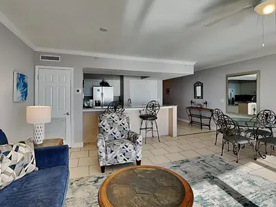 a living room with a table and chairs and a kitchen at Emerald Beach #1927 in Panama City Beach