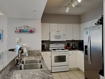 a kitchen with white cabinets and a stainless steel refrigerator at Emerald Beach #1927 in Panama City Beach