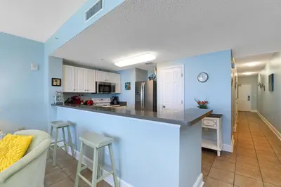 a kitchen and living room with blue walls and a counter at Majestic Beach Towers I #1105 in Panama City Beach