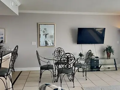 a dining room with a table and chairs and a tv at Emerald Beach #1827 in Panama City Beach