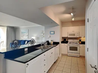 a kitchen with white cabinets and a blue counter top at Emerald Beach #1827 in Panama City Beach