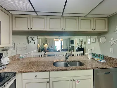a kitchen with a sink and a living room at Edgewater Tower II 809 in Panama City Beach