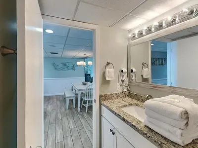 a bathroom with a sink and a mirror and a table at Edgewater Tower II 809 in Panama City Beach