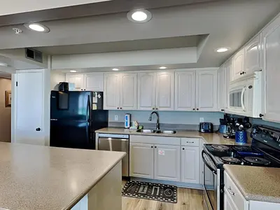 a kitchen with white cabinets and a black refrigerator at Edgewater Tower Iii 213 in Panama City Beach