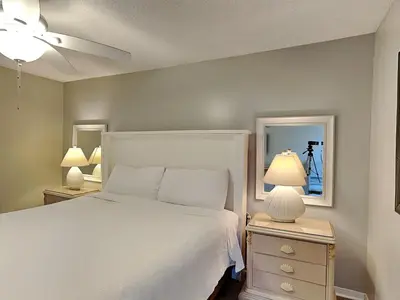 a bedroom with a bed and two night stands with lamps at Edgewater Tower Iii 213 in Panama City Beach