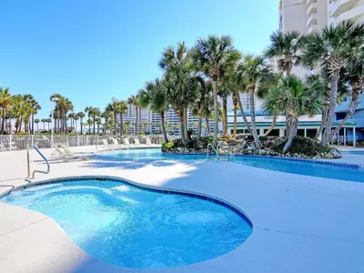 a swimming pool with palm trees and a building at Long Beach Resort Tower IV #407 in Panama City Beach