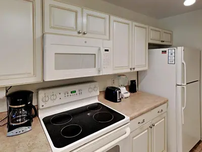 a kitchen with white cabinets and a stove and refrigerator at Edgewater Villa #814 in Panama City Beach