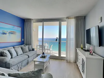 a living room with a couch and a television with a view at Majestic Beach Towers I #1703 in Panama City Beach