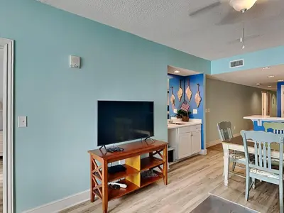 a living room with a flat screen tv and a table at Majestic Beach Towers II #1106 in Panama City Beach