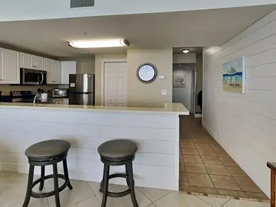 a kitchen with two bar stools and a counter with a clock at Majestic Beach Towers I #1311 in Panama City Beach