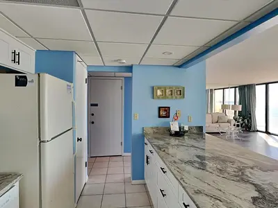 a kitchen with blue walls and a white refrigerator at Edgewater Tower III #302 in Panama City Beach