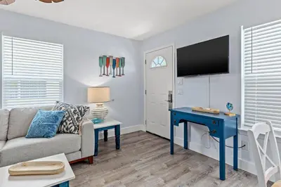 a living room with a couch and a table and a tv at Top Shelf 47 Unit C in Panama City Beach