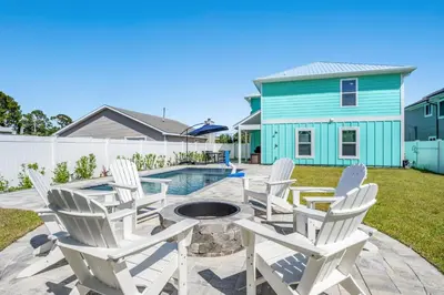 a patio with chairs and a fire pit in front of a house at Heated Pool & Pet Friendly - Minutes To Beach - Spacious Backyard - FLPCB38 in Panama City Beach