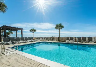 a large swimming pool with chairs and palm trees at Ocean Villa 803 in Panama City Beach