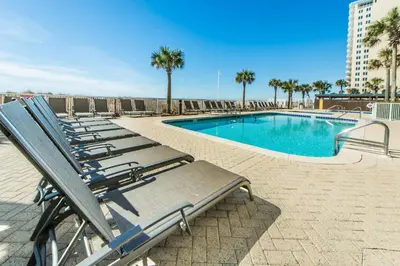 a row of lounge chairs next to a swimming pool at Ocean Villa 803 in Panama City Beach