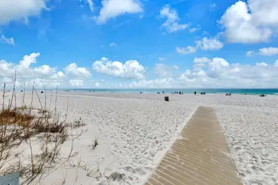 a sandy beach with a wooden pathway to the ocean at Sunbird 211E in Panama City Beach