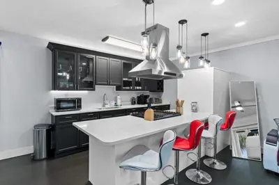 a kitchen with black and white cabinets and red chairs at Splash Pad by Book That Condo in Panama City Beach
