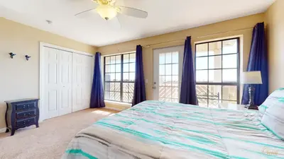 a bedroom with a bed with blue curtains and windows at Near Pier Park and Beach - Pools Onsite - FLPCB66 in Panama City Beach