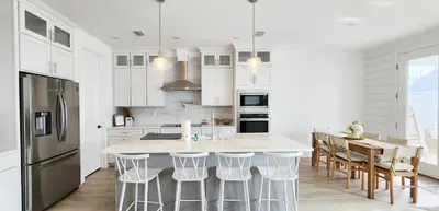 a kitchen with white cabinets and a kitchen island with bar stools at Flounder by the Sea in Panama City Beach