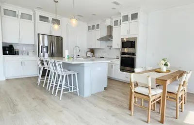 a kitchen with white cabinets and a table and chairs at Flounder by the Sea in Panama City Beach