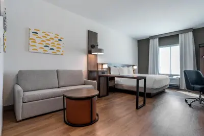 a hotel room with a couch and a bed and a desk at Comfort Inn & Suites Panama City Beach - Pier Park Area in Panama City Beach