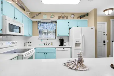 a kitchen with blue cabinets and a white refrigerator at Gulf Highlands 220 in Panama City Beach